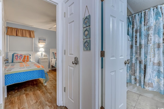 bedroom featuring a textured ceiling, ornamental molding, and tile patterned floors