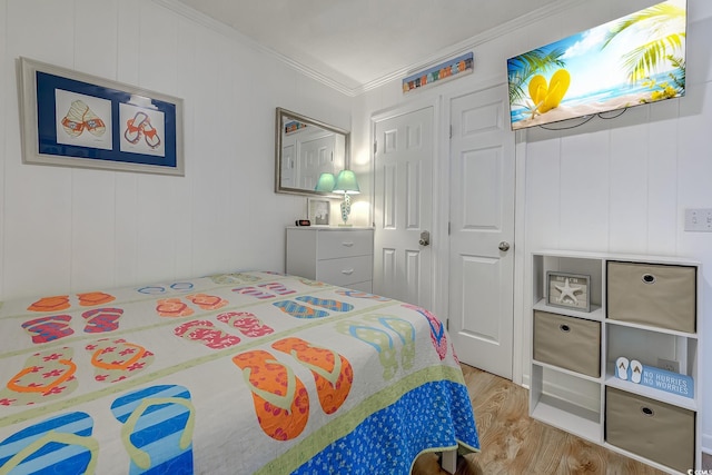bedroom with ornamental molding and wood finished floors