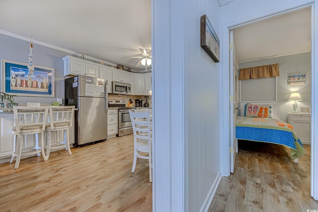 interior space with light wood-type flooring, appliances with stainless steel finishes, ceiling fan, and white cabinetry