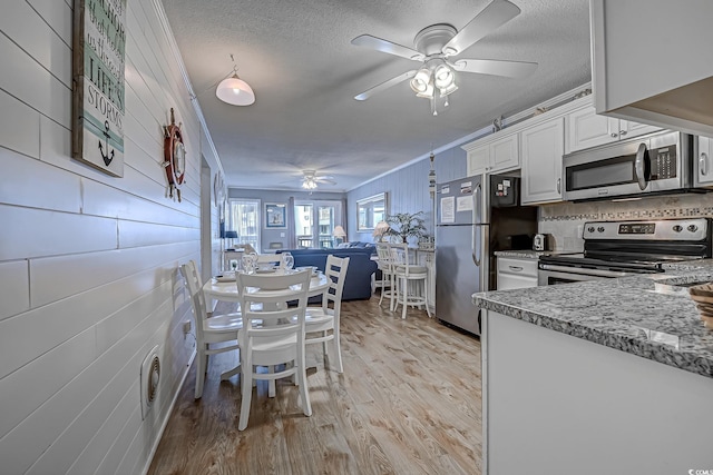 kitchen featuring light wood-style flooring, a textured ceiling, white cabinetry, a ceiling fan, and appliances with stainless steel finishes