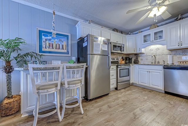 kitchen with white cabinets, light wood-type flooring, and appliances with stainless steel finishes