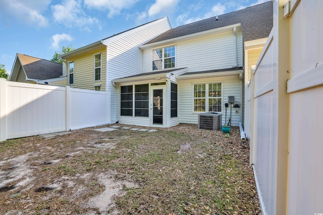 rear view of property with fence, central air condition unit, a shingled roof, and a sunroom