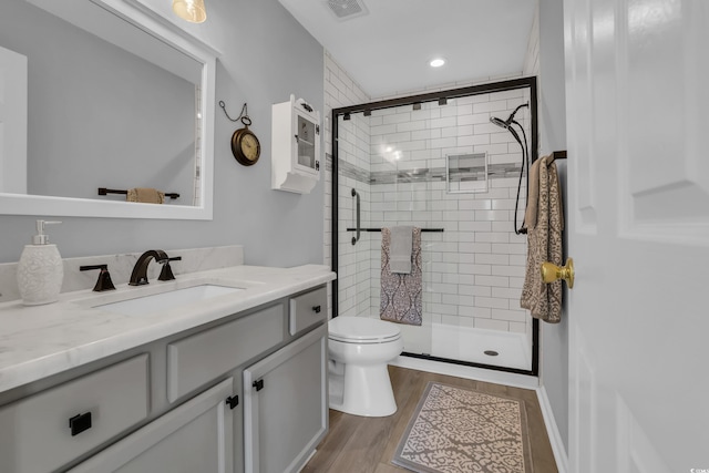 bathroom featuring wood finished floors, visible vents, toilet, and a shower stall