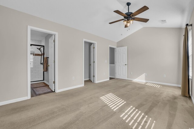 unfurnished bedroom with connected bathroom, light colored carpet, a walk in closet, baseboards, and lofted ceiling