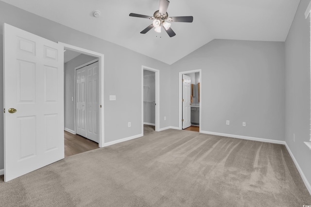 unfurnished bedroom with baseboards, carpet floors, connected bathroom, vaulted ceiling, and a walk in closet