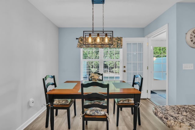 dining space featuring a notable chandelier, light wood-style flooring, and baseboards
