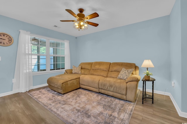 living room featuring a ceiling fan, visible vents, wood finished floors, and baseboards
