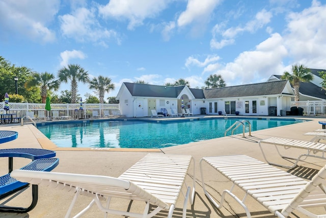 community pool with a patio and fence