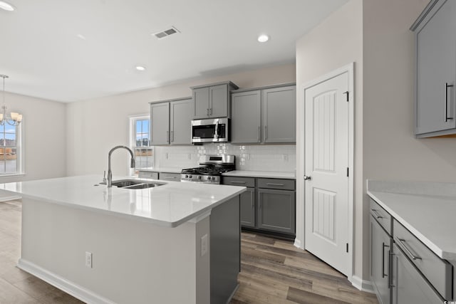 1513 Anne St, North Myrtle Beach, SC 29582 - kitchen featuring stainless steel appliances, gray cabinets, dark wood-style flooring, tasteful backsplash, and a center island with sink