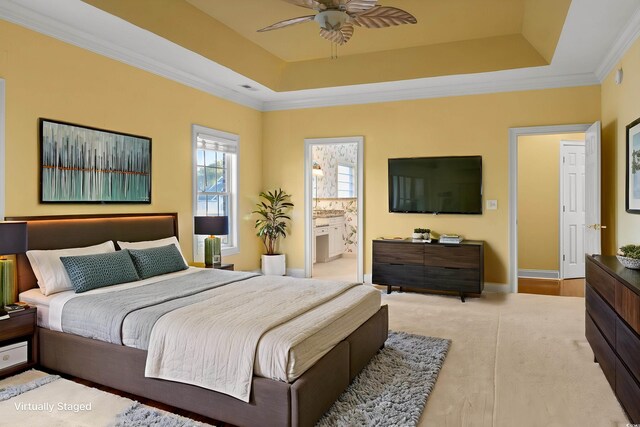 bedroom with baseboards, ensuite bathroom, crown molding, a tray ceiling, and ceiling fan