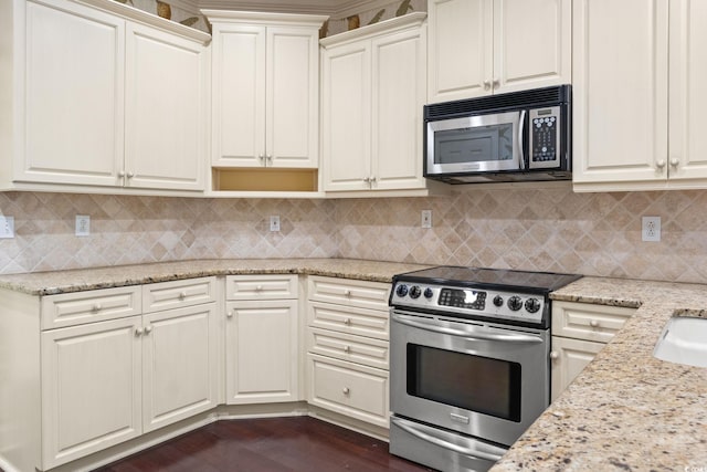 kitchen with decorative backsplash, dark wood finished floors, light stone countertops, and stainless steel appliances