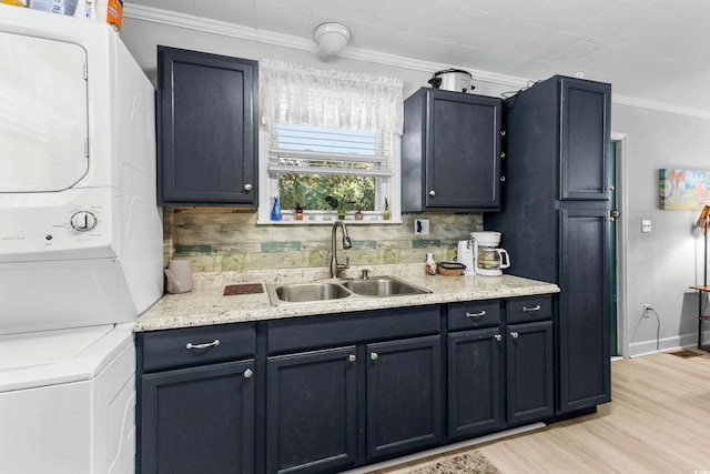 kitchen with stacked washer and dryer, ornamental molding, a sink, and light wood-style flooring