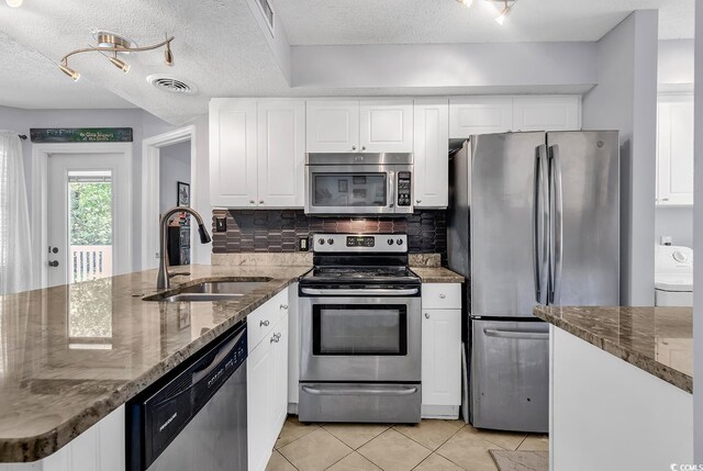 157 Egret Run Ln Unit 514, Pawleys Island, SC 29585 - kitchen with appliances with stainless steel finishes, a peninsula, light tile patterned floors, decorative backsplash, and dark stone counters
