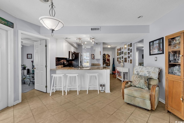 157 Egret Run Ln Unit 514, Pawleys Island, SC 29585 - kitchen featuring light tile patterned flooring, a breakfast bar area, a peninsula, a textured ceiling, and white cabinets