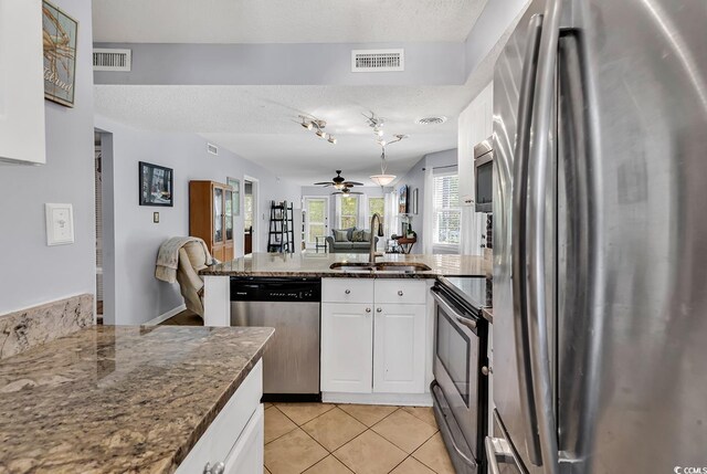 157 Egret Run Ln Unit 514, Pawleys Island, SC 29585 - kitchen featuring appliances with stainless steel finishes, a peninsula, white cabinetry, light tile patterned flooring, and open floor plan