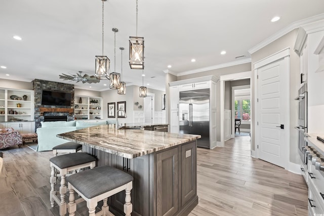 1006 Surf Pointe Dr, North Myrtle Beach, SC 29582 - kitchen featuring stainless steel appliances, a sink, ornamental molding, a spacious island, and light stone countertops