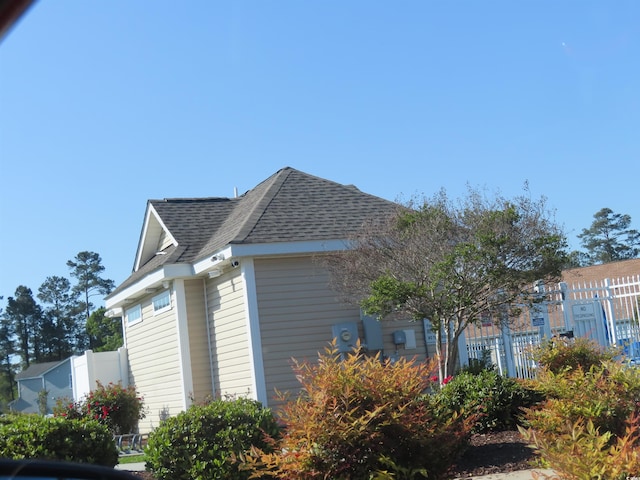 view of side of property with roof with shingles and fence
