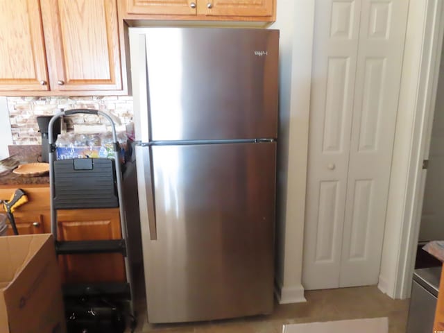 kitchen featuring backsplash, freestanding refrigerator, and tile patterned flooring