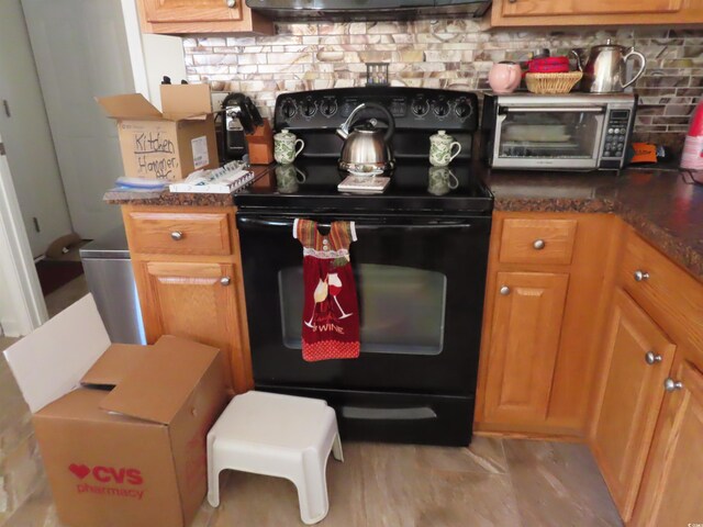 kitchen with a toaster, brown cabinets, black range with electric stovetop, and decorative backsplash