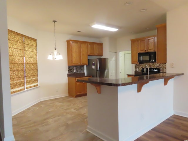 819 Brookline Dr, Myrtle Beach, SC 29579 - kitchen with black microwave, freestanding refrigerator, a peninsula, decorative backsplash, and dark countertops
