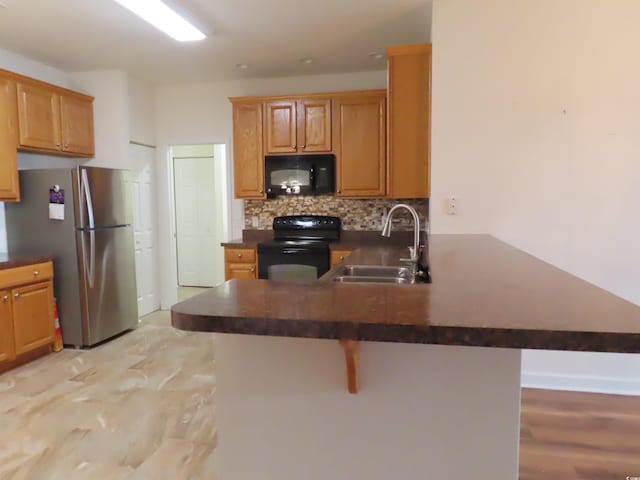 819 Brookline Dr, Myrtle Beach, SC 29579 - kitchen featuring black appliances, a sink, dark countertops, decorative backsplash, and a breakfast bar