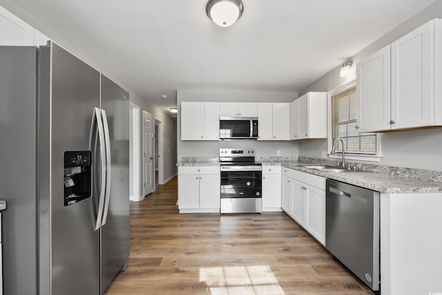 kitchen featuring light wood-style flooring, white cabinetry, a sink, and appliances with stainless steel finishes