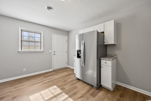kitchen with white cabinets, light wood-type flooring, baseboards, and stainless steel fridge