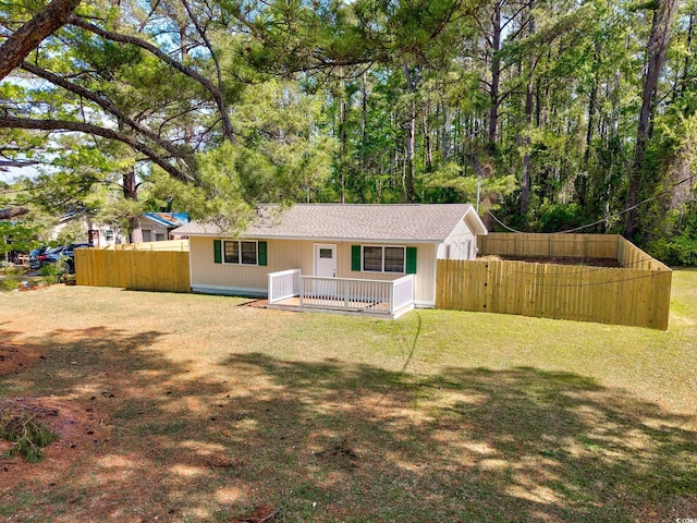 rear view of house featuring a yard and fence