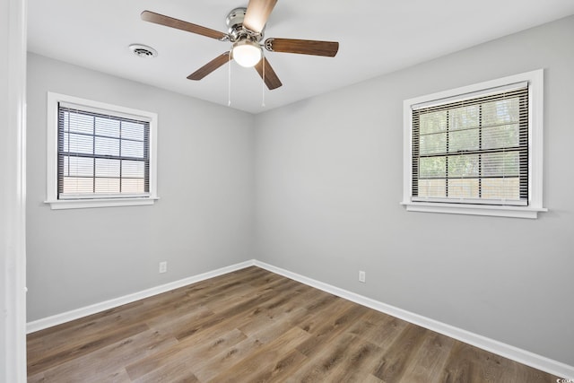 empty room with visible vents, baseboards, plenty of natural light, and wood finished floors