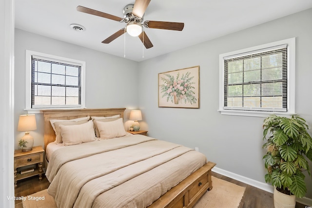 bedroom with visible vents, baseboards, multiple windows, and wood finished floors
