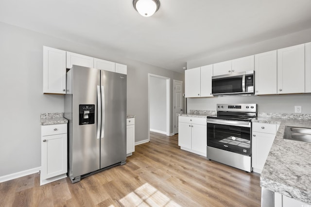 kitchen featuring light wood-style flooring, white cabinetry, baseboards, and appliances with stainless steel finishes