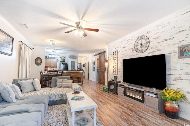 living area featuring crown molding, ceiling fan, visible vents, and light wood-style floors