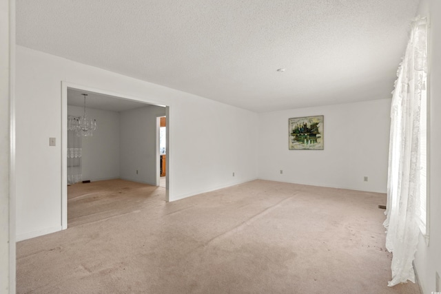 spare room featuring carpet floors, a textured ceiling, and an inviting chandelier