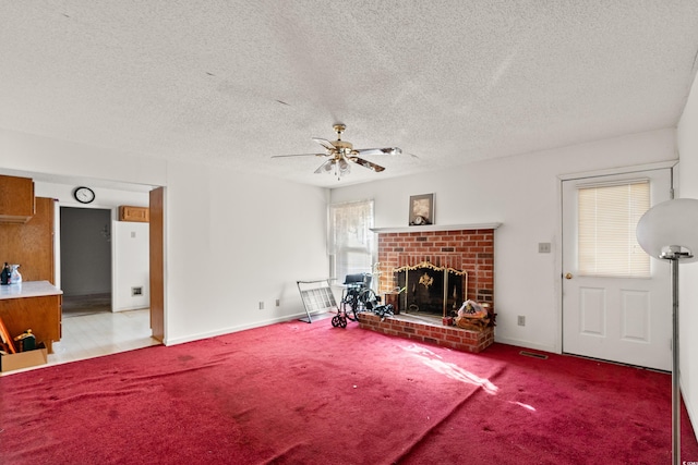 living area with a ceiling fan, a textured ceiling, carpet, baseboards, and a brick fireplace
