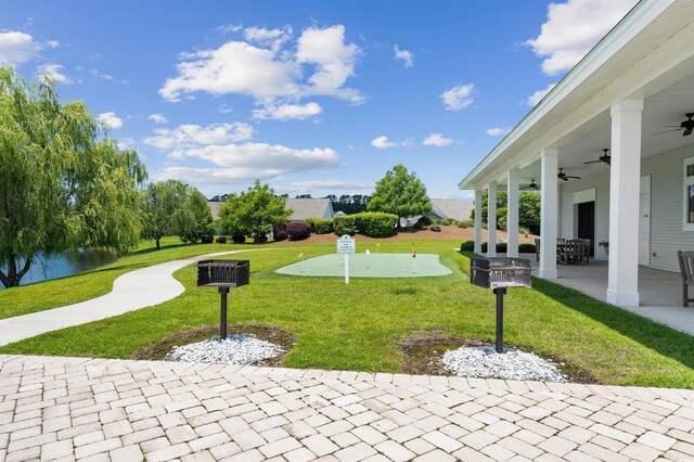 view of grassy yard with an area to practice putting, ceiling fan, and a patio