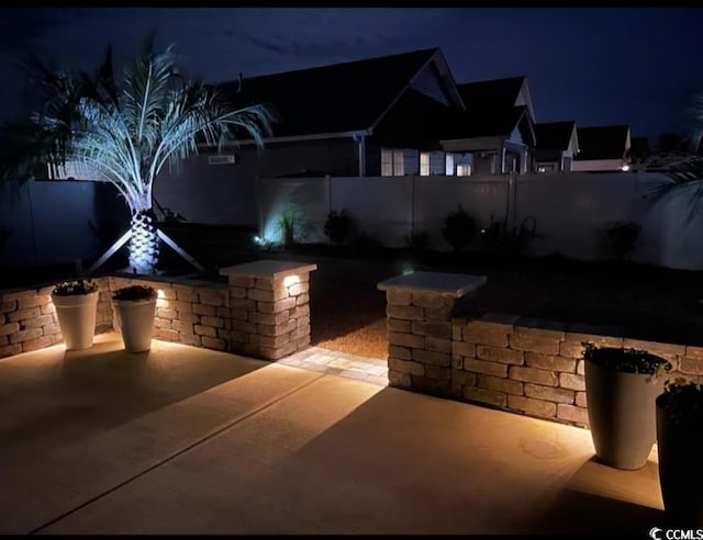 patio at night featuring a fenced backyard