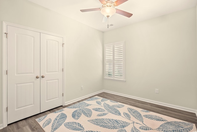 unfurnished bedroom featuring wood finished floors, baseboards, a closet, and ceiling fan