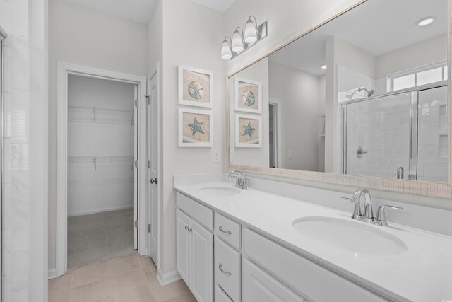 full bathroom with a shower stall, a spacious closet, double vanity, and tile patterned floors