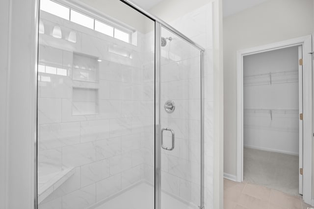 bathroom featuring a shower stall, a spacious closet, and tile patterned floors
