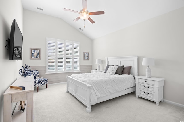 bedroom with light carpet, a wainscoted wall, vaulted ceiling, and ceiling fan