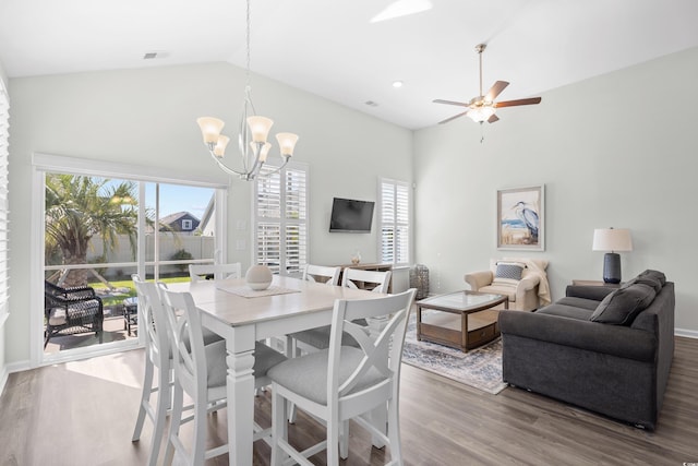 dining space featuring wood finished floors, healthy amount of natural light, a chandelier, a ceiling fan, and high vaulted ceiling