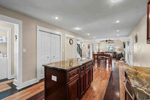 kitchen featuring wood-type flooring, washer / dryer, vaulted ceiling, and ceiling fan