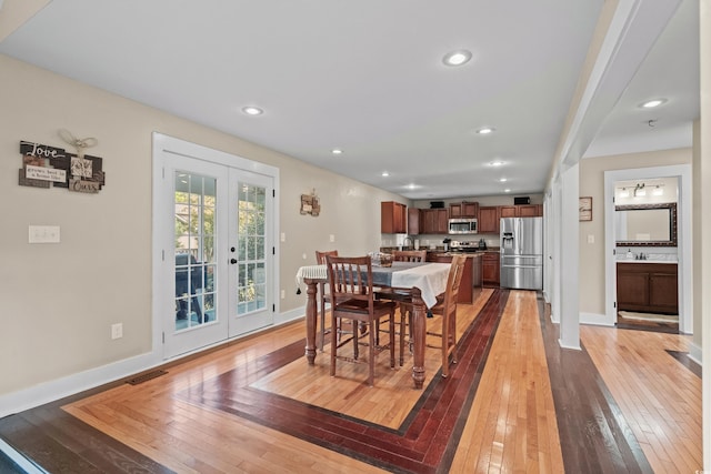 dining space with light wood-style floors, french doors, baseboards, and visible vents