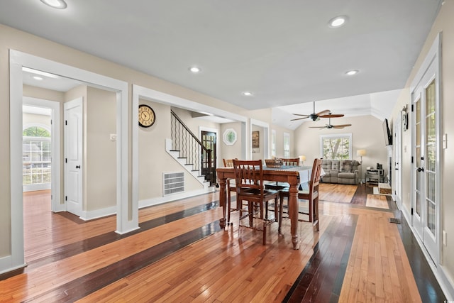 dining space featuring light wood-type flooring, a wealth of natural light, visible vents, and stairs