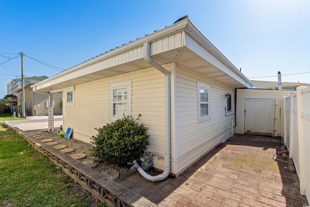 view of side of home featuring a patio, fence, and a gate