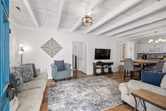 living area with wood finished floors, beamed ceiling, a notable chandelier, and visible vents