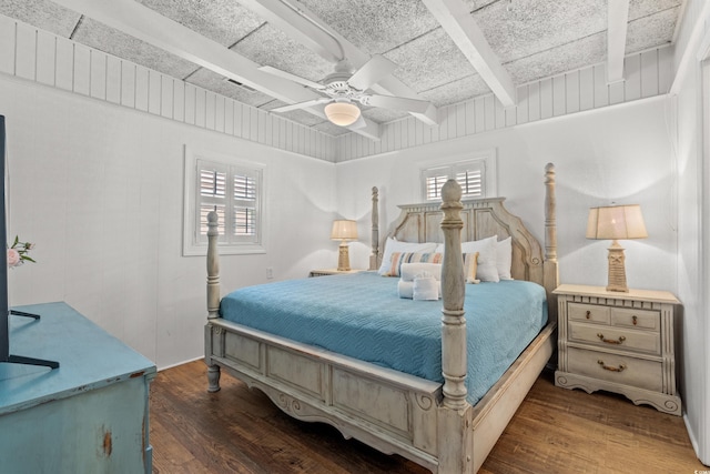 bedroom featuring wood finished floors, beamed ceiling, and multiple windows