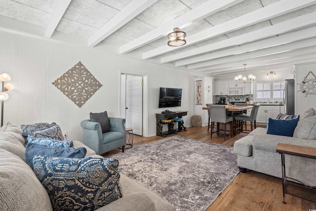living area featuring beamed ceiling, an inviting chandelier, and wood finished floors