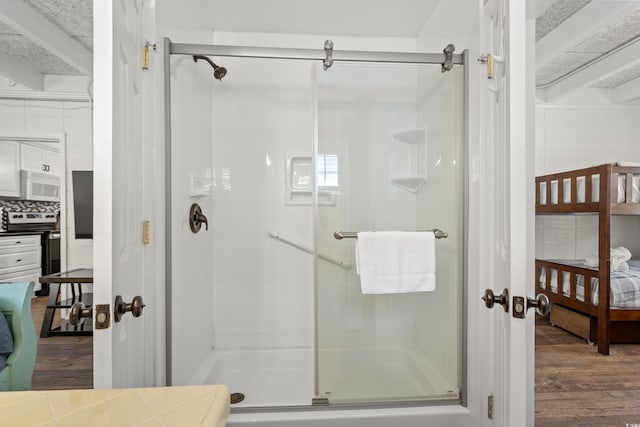 ensuite bathroom with a stall shower, connected bathroom, and wood finished floors