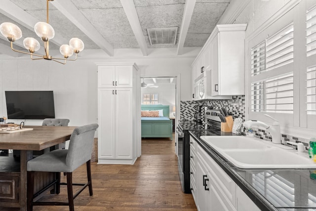 kitchen featuring white microwave, electric range, backsplash, dark wood-type flooring, and visible vents